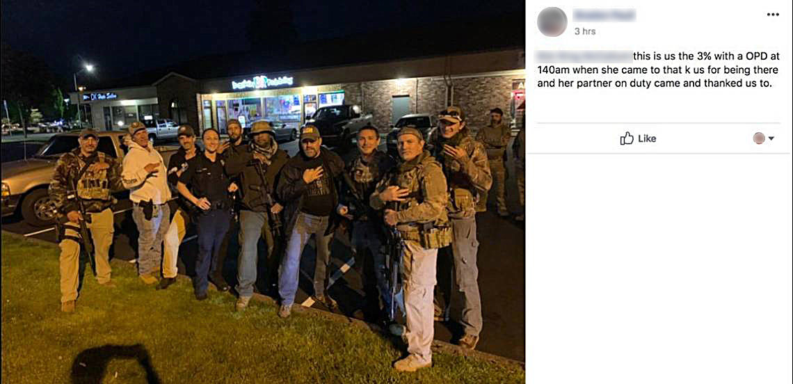 In a photo posted to Facebook, Olympia police officer Tiffany Coates poses with a group of armed men, many of whom can be seen making hand gestures associated with the Three Percent movement. Coates was responding to a call at a gun shop parking lot in the early hours of June 5. (Facebook)